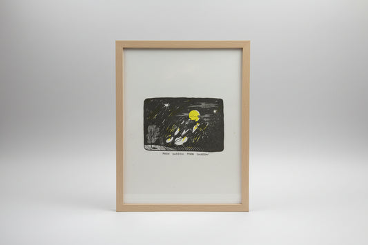 A square art print or illustration on white paper showing a dark night scene with a bright yellow moon, white stars, streaks of light, and a tree silhouette. Handwritten text below reads 'MOON SHADOW, MOON SHADOW'.