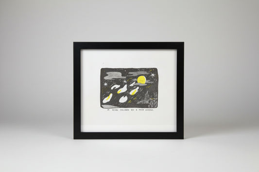 A hand-drawn style art print or card featuring a night sky scene with a yellow moon, stars, and several white and yellow moon phases. Below the illustration, handwritten text reads, 'I'M BEING FOLLOWED BY A MOON SHADOW.
